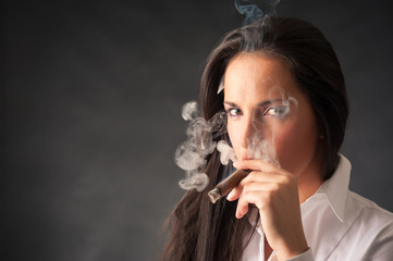 Portrait of woman smoking cigar. Studio fashion photo on dark ba