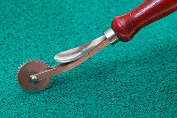 sewing tracing wheel on green textile