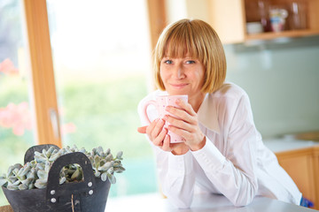 Happy mid aged woman with coffee at home