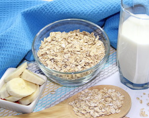 Oat flakes in bowl, milk and bananas
