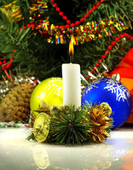 image of a burning candle near a Christmas tree