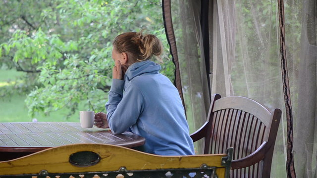 Lady drinking hot morning coffee in garden bower