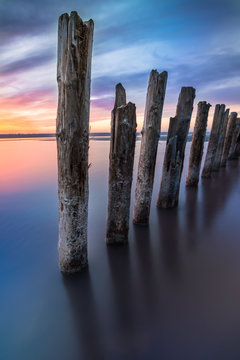 Fototapeta Unusual pillars in the water on the background of colorful sky