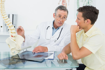 Obraz premium Doctor explaining spine to patient in office