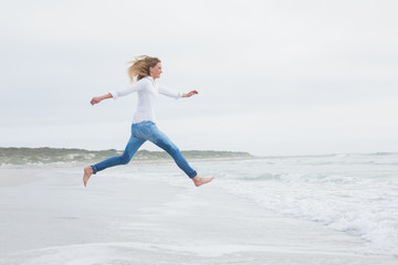 Fototapeta na wymiar Side view of a casual woman jumping at beach