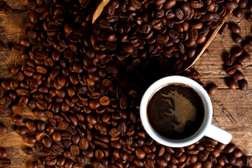 Cup of coffee with coffee beans and wooden ladle