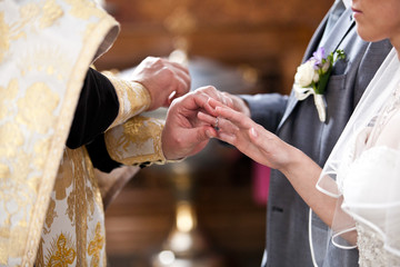 orthodox bishop putting golden rings on bride and grooms hands