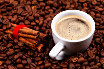 Cup of coffee with cinnamon on coffee beans