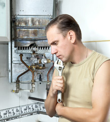 The man with a wrench thinks of repair of a gas water heater..