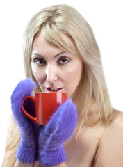 Portrait of the young blonde woman in fluffy mittens with a mug