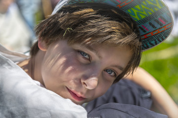 sitting boy with base cap looking into the camera