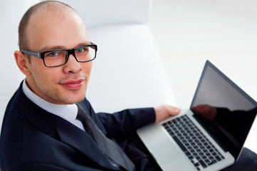 Young smiling businessman sitting with laptop