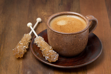 cup of coffee and caramel sugar on sticks