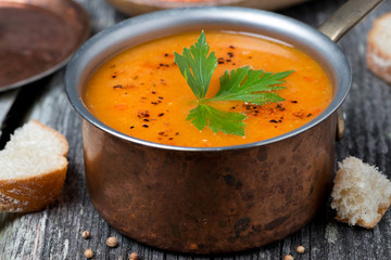 Spicy red lentil soup in a copper saucepan, close-up