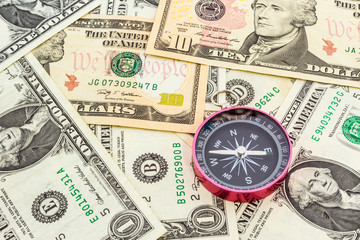 Compass on a heap of paper dollars.