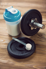 Obraz na płótnie Canvas Bodybuilding supplement and a dumbbell, vertical shot