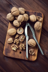 Vintage cutting board with walnuts and nutcracker, above view