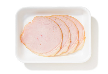 Four slices of fat roll ham with rind in a foam tray, isolated on white background