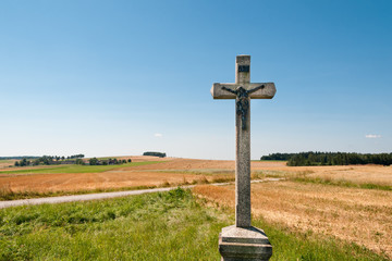 altes Kreuz vor abgeernteten Feldern