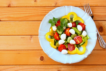 salad with mozzarella and fresh vegetables on wooden table backg