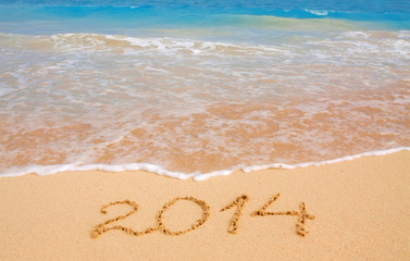 Fototapeta na wymiar Year 2014 written in sand on tropical beach .
