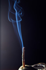 Burning cigarette with smoke on black background