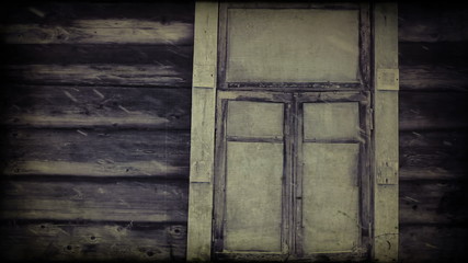 Snowing against the window of an old wooden blockhouse
