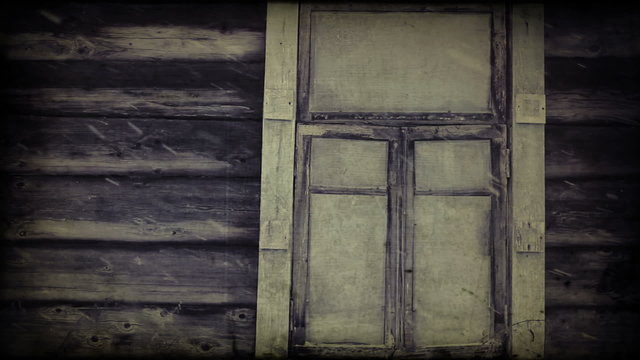 Snowing against the window of an old wooden blockhouse