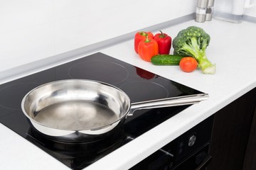 Frying pan and vegetables in modern with induction stove