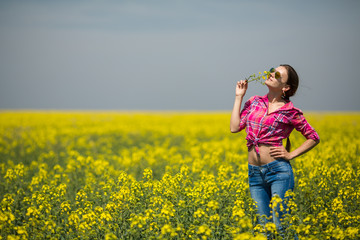 Naklejka na ściany i meble Young beautiful woman in flowering field in summer. Outdoors