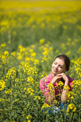 Fototapeta premium Young beautiful woman in flowering field in summer. Outdoors