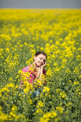 Naklejka premium Young beautiful woman in flowering field in summer. Outdoors