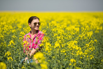 Young beautiful woman in flowering field in summer. Outdoors