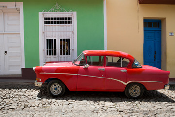 Roter Oldtimer vor bunten Häusern, Kuba