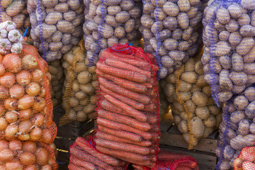 Vegetables in big bags at vegetable street market - carrots, oni