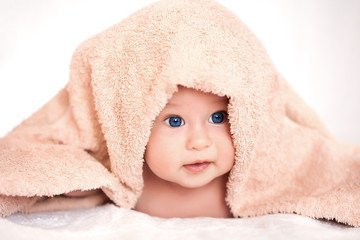 baby girl is hiding under the beige terry towel