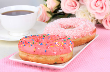 Obraz na płótnie Canvas Sweet donuts with cup of tea on table on light background