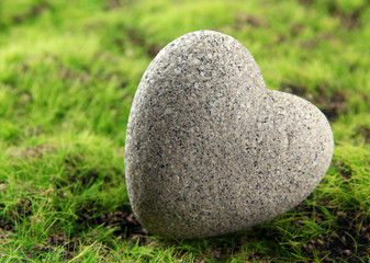 Grey stone in shape of heart, on grass background
