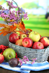 Juicy apples in basket on table on natural background