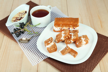 Tasty sherbet with nuts on plate on wooden table close-up