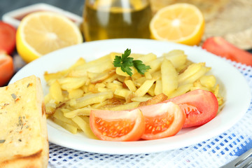 Ruddy fried potatoes on plate on wooden table close-up
