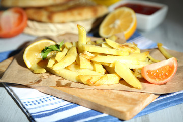 Ruddy fried potatoes on wooden board on table close-up