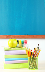 School supplies on table on blackboard background