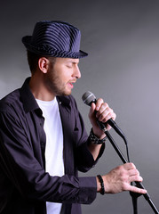 Fototapeta na wymiar Young musician singing, on gray background