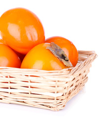 Ripe persimmons in wicker basket isolated on white