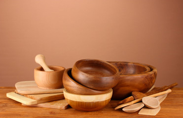 Wooden kitchen utensils on table on brown background