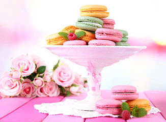 Gentle macaroons in vase on table on light background