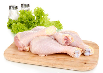 Raw chicken legs on wooden board close up