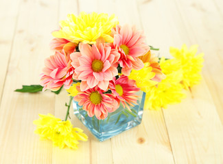 Fototapeta na wymiar Chrysanthemum flowers in vase on wooden table close-up
