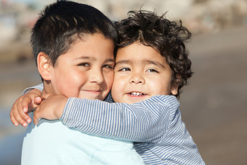 close up portrait of two cute little hispanic brothers hugging each other on a summer sunny day